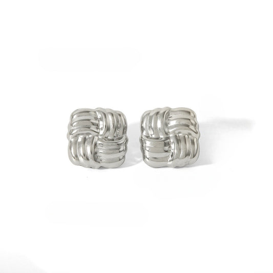 Two square silver-colored knot earrings on a white surface.