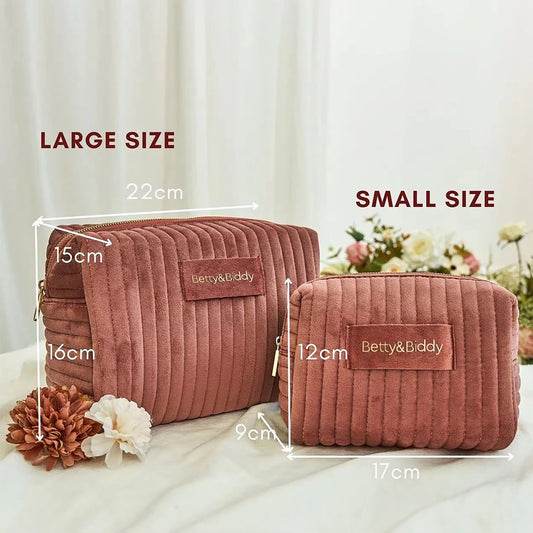 Two rose-colored, corduroy "Betty & Biddy" bag cosmetic bags are presented in large and small sizes with dimension labels.