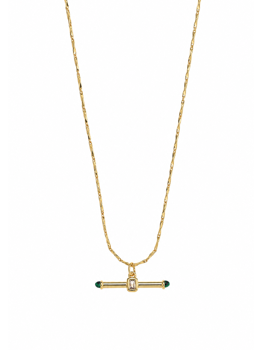 The Jewelled T Bar Necklace features a horizontal gold bar pendant set with a clear emerald-cut stone at the center and green stones capping each end. It hangs from a delicate twisted gold chain