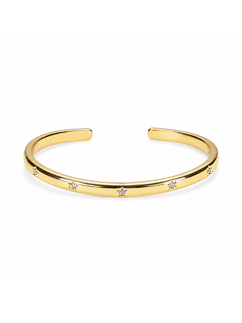 A polished gold cuff bracelet with small, evenly spaced clear crystal accents, displayed on a clean white background.