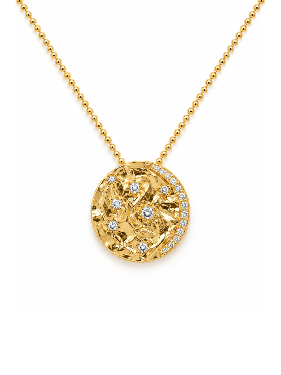A gold ball-chain necklace with a round pendant featuring a textured floral pattern accented with small clear stones, shown on a plain white background.